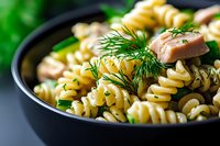 Delicious fusilli pasta with fresh mushrooms and dill herbs in black pan, perfect for Italian cuisine recipes and cooking blogs.