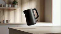 Modern black electric kettle on white kitchen counter with wooden shelving and ceramic dishware in contemporary minimalist home interior design.