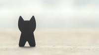 Minimalist black cat silhouette standing alone on textured surface against soft blurred background creates moody atmospheric composition.