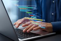 Professional businessman typing on laptop with colorful digital data streams and programming code visualization for modern technology concepts.