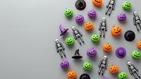 Halloween decorations with colorful pumpkins, skeletons, witch hats and spooky ornaments scattered on gray background for festive party planning.