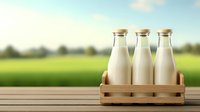 Fresh milk bottles in rustic wooden crate on table against blurred green meadow background, natural dairy farm concept for packaging and advertising.