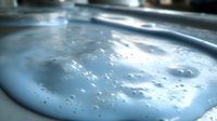 Macro shot of soap foam bubbles creating abstract texture with light blue tones and reflective surface, showing delicate details and natural patterns.