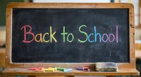 Colorful chalk text Back to School written on black chalkboard with wooden frame and colored chalks, education concept for classroom learning and academic year.