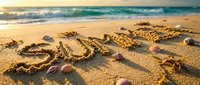 Summer written in golden sand on a sunny tropical beach with seashells and turquoise ocean waves in the background at sunset.
