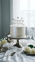 Elegant white birthday cake with silver star topper on vintage pedestal stand, white roses and champagne glasses on draped table.