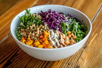Fresh buddha bowl with quinoa, roasted butternut squash, red cabbage, kale, chickpeas and creamy tahini dressing on wooden table, healthy lunch concept.