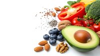 Fresh healthy foods avocado nuts berries vegetables on white background for nutritious diet meal planning and clean eating lifestyle.