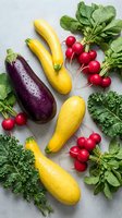 Fresh organic vegetables including yellow squash, purple eggplant, red radishes and leafy greens arranged on white marble surface for healthy cooking.