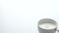 White ceramic coffee cup filled with fresh milk on clean white background isolated for design and commercial use.