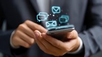 Business professional using smartphone with glowing message icons floating above, demonstrating modern mobile communication and digital messaging technology.