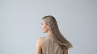 Woman with long straight hair in profile view against neutral background, suitable for beauty, haircare, wellness and lifestyle design projects.