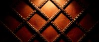 Luxury brown leather upholstery with diamond quilted pattern and decorative stitching creates elegant texture for premium interior design and furniture applications.