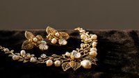 Elegant golden leaf jewelry set with pearls on dark velvet background for luxury fashion and accessories photography.