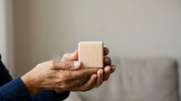 Mature man with dark skin holding blank wooden cube in open palm, suitable for business concepts, decision-making, and corporate messaging applications.