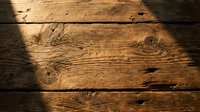 Rustic wooden planks with natural grain patterns and knots illuminated by warm sunlight creating dramatic shadows across weathered timber surface.