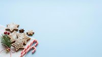 Decorated gingerbread cookies with white icing, candy canes, and evergreen sprigs arranged on light blue background for holiday baking and festive season designs.