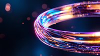 Glowing spiral light trail with vibrant neon colors blue, pink and orange against dark background creates dynamic motion effect with bokeh elements.