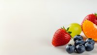 Fresh mixed fruits strawberries blueberries grapes orange on white background for healthy eating nutrition diet wellness food photography.