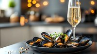 Steamed mussels served on dark plate with fresh herbs and glass of sparkling wine, romantic dinner setting with bokeh lights in modern restaurant interior.