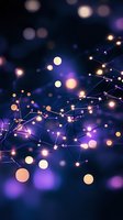 Glowing string lights creating magical bokeh effect against dark blue background with purple and golden illuminated spots. Festive holiday atmosphere.