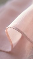 Soft pink linen fabric roll with natural texture and gentle lighting for textile design and crafting projects.