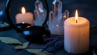 Burning candles with lavender sprigs and mirror reflection create peaceful spa atmosphere for relaxation and aromatherapy wellness rituals.