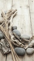 Natural spa composition with driftwood, smooth stones, dried grass and bark on rustic wooden planks for wellness and relaxation design concepts.