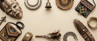 Vintage collection of tribal artifacts, masks, horseshoes, compass and rustic objects arranged in circular frame on neutral background for design projects.