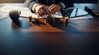 Business professional arranging wooden blocks on desk with coffee cup and documents in modern office setting for strategic planning concepts.