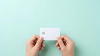 Hands holding blank white credit card or business card against soft mint green background for mockup and branding purposes.