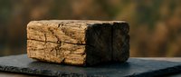 Weathered wooden blocks with natural grain texture and charred surface on slate background, suitable for construction, carpentry, and industrial design projects.