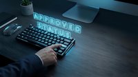 Businessman's hand on mechanical keyboard with glowing "Approved" neon text, modern workspace setup with laptop and plant for business approval concepts.