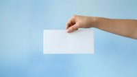 Hand holding blank white card against blue background for advertising and branding mockup purposes.