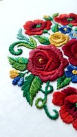 Colorful floral embroidery with red roses and blue flowers on white fabric showcasing traditional needlework craftsmanship for textile and fashion design projects.