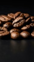 Roasted coffee beans close-up on dark background showcasing rich brown texture and natural cracks for cafe branding and beverage marketing materials.