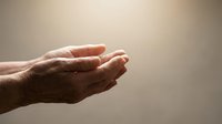 Open cupped hands in prayer or receiving gesture against soft beige background symbolizing hope, faith, spirituality and divine connection.