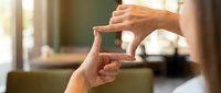 Female hands forming frame gesture for creative composition and photography planning in bright indoor setting.