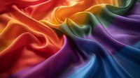 Smooth flowing rainbow colored silk fabric with elegant folds and waves creating dynamic movement and light reflection. Suitable for luxury fashion and design projects.