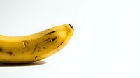 Ripe yellow banana with dark spots isolated on white background, ready for food and nutrition design projects.