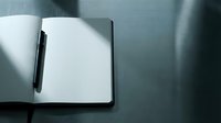 Open notebook with blank white pages and black pen on gray surface, ready for writing, planning, or business note-taking.