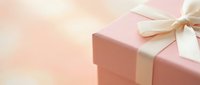 Pink gift box with white satin ribbon bow on soft pastel background for celebrations, holidays, birthdays, anniversaries and special occasions.