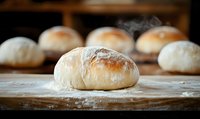 Fresh baked artisan bread rolls on wooden surface with flour dusting, warm bakery atmosphere perfect for culinary and food service applications.