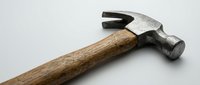 Vintage claw hammer with weathered wooden handle and metal head isolated on white background for construction and carpentry projects.
