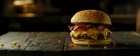 Juicy cheeseburger with melted cheese, bacon and beef patty on rustic wooden table in dark moody lighting, panoramic food photography.