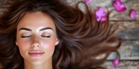 Young woman with flowing brown hair lying on wooden surface surrounded by pink orchid flowers, eyes closed in peaceful relaxation, natural beauty spa concept.