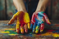 Hands covered in vibrant multicolored paint resting on canvas during creative art session. Suitable for artistic expression, creativity, and design projects.