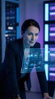 Woman in dark business suit analyzing holographic data displays and financial charts in high-tech server room environment with neon blue and purple lighting for technology and finance concepts.