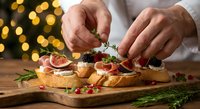 Professional chef hands garnishing gourmet appetizers with fresh herbs on wooden board. Festive holiday catering with warm bokeh lights background.