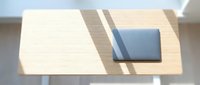 Overhead view of organized workspace with blue notebook and striped desk pad on light wooden surface, suitable for business and productivity content.